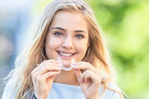 Woman inserting Invisalign teeth alignment device